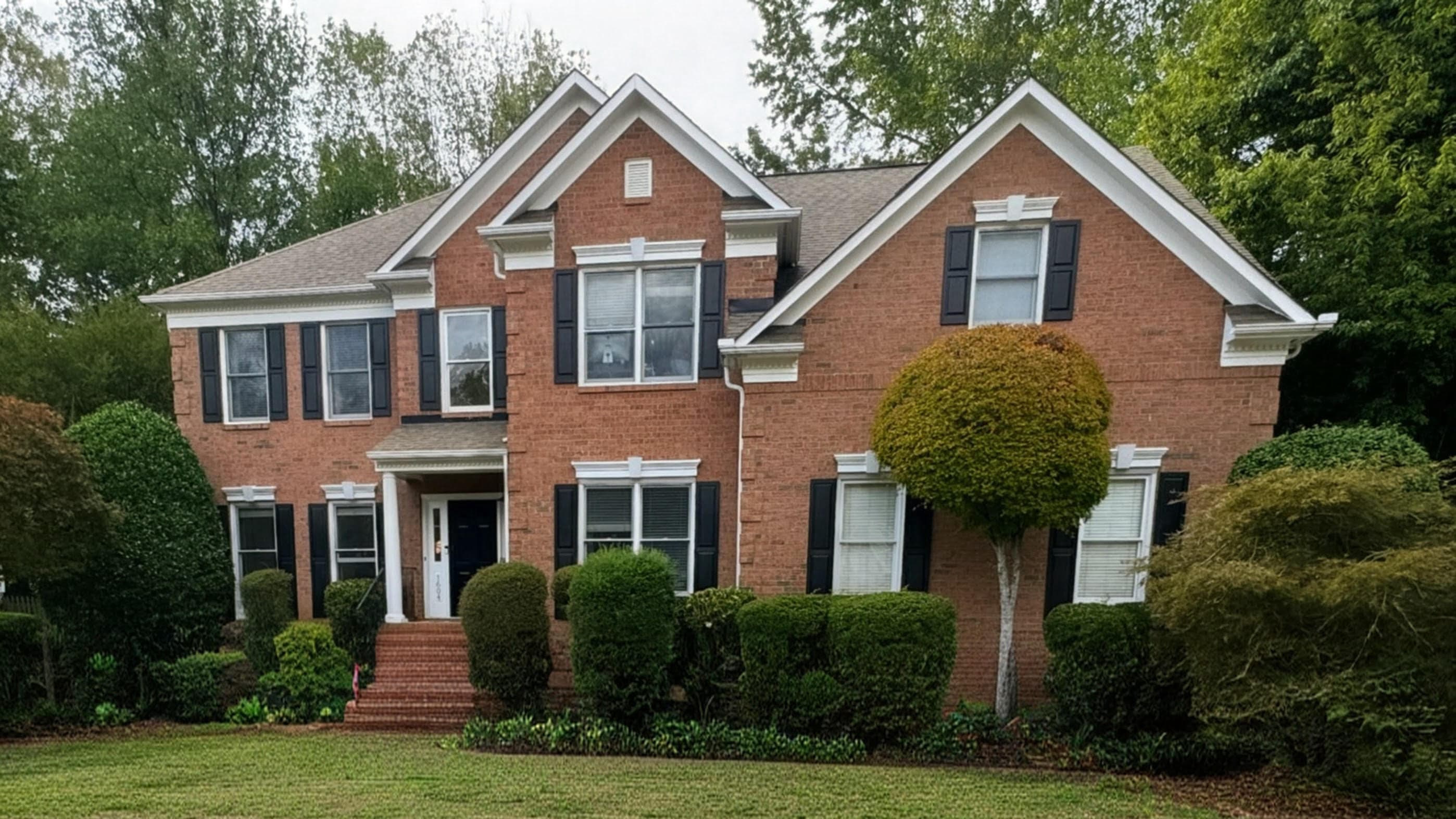 Brick colonial home in Charlotte with a clean roofline after roofing work.