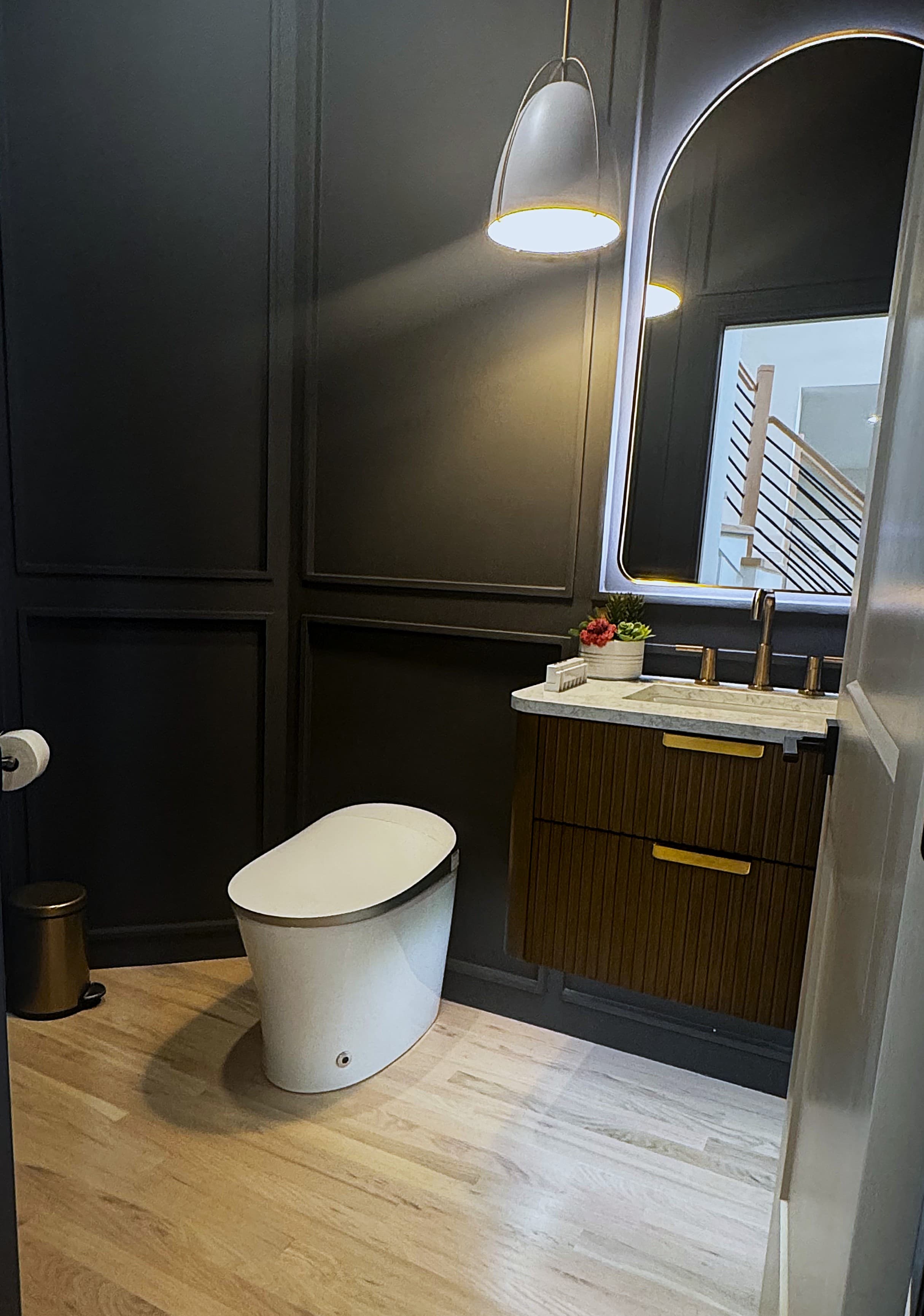 Luxury Charlotte powder room with dramatic dark walls, fluted vanity, and arched mirror.